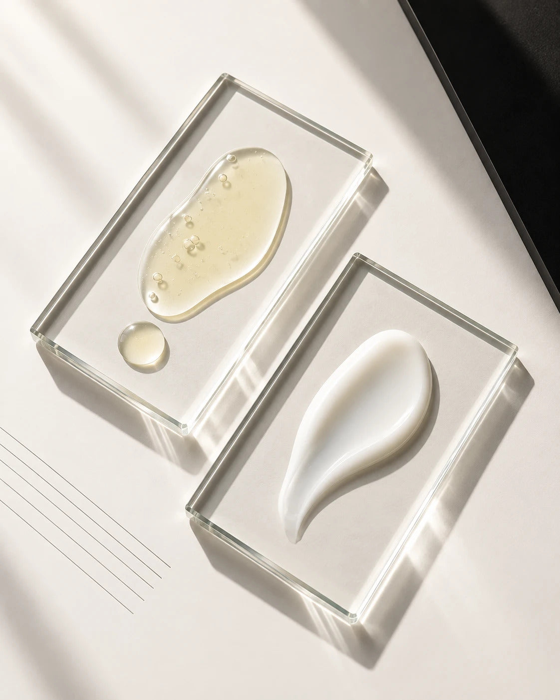The Longevity Hybrid Defense Serum and Revolumizing Bioactive Moisturizer textures on glass blocks in daylight